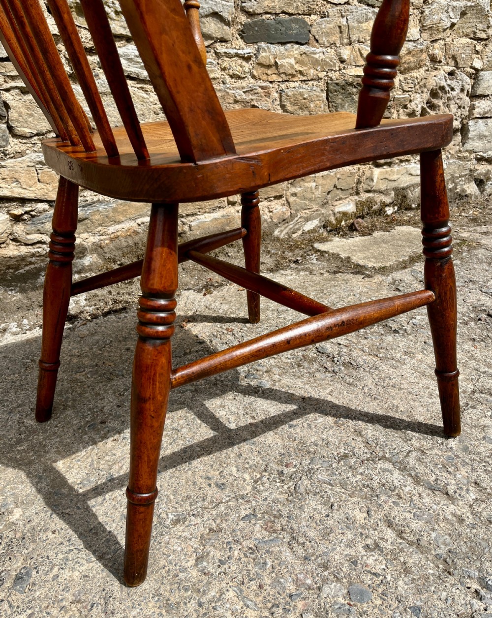 An antique wooden Windsor armchair featuring vertical back spindles, turned legs, curved armrests, and a shaped saddle seat. View VIII