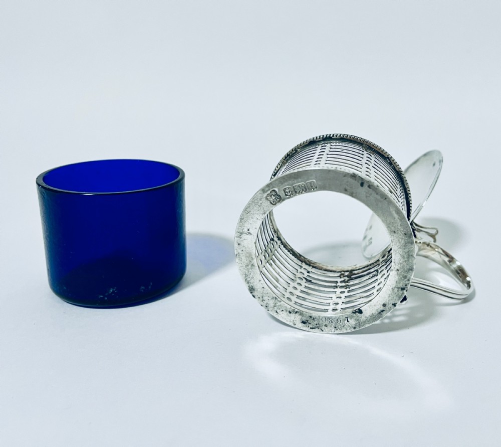 A cylindrical pierced silver mustard pot featuring a hinged lid, side handle, beaded borders, and a cobalt blue glass liner. View IX