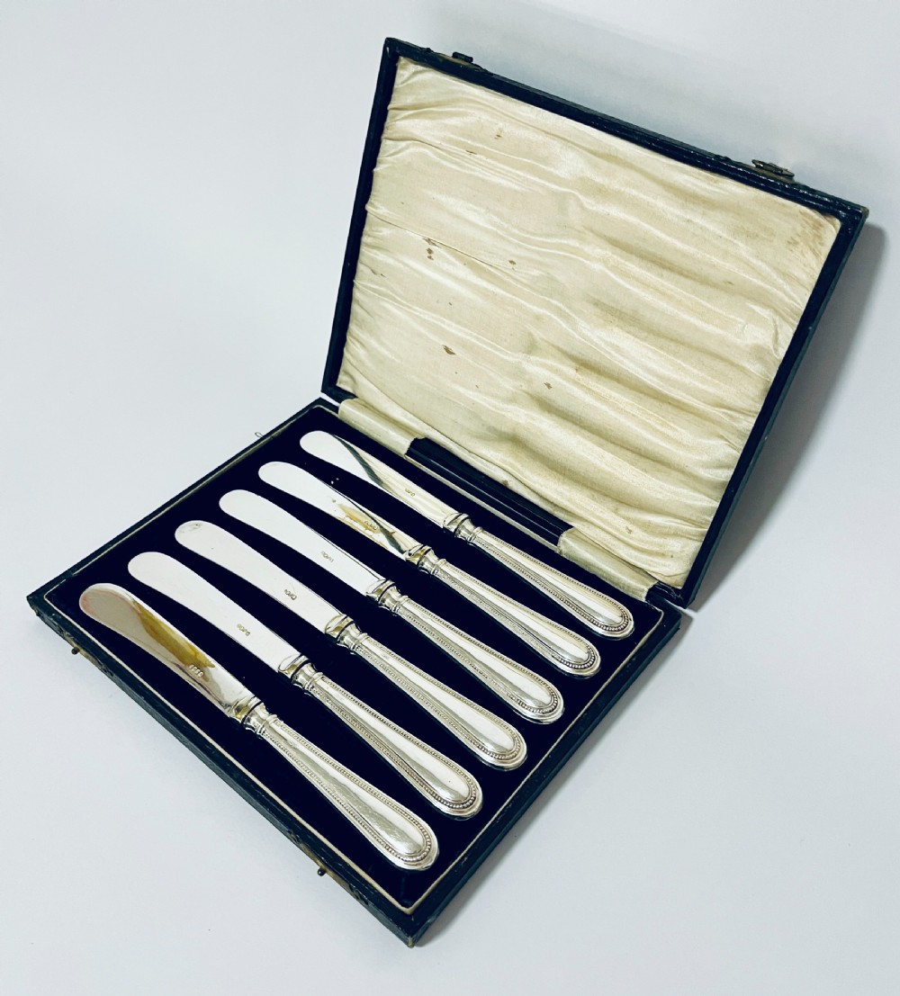 A set of six antique silver-handled butter knives arranged inside a velvet and satin lined presentation case. View II