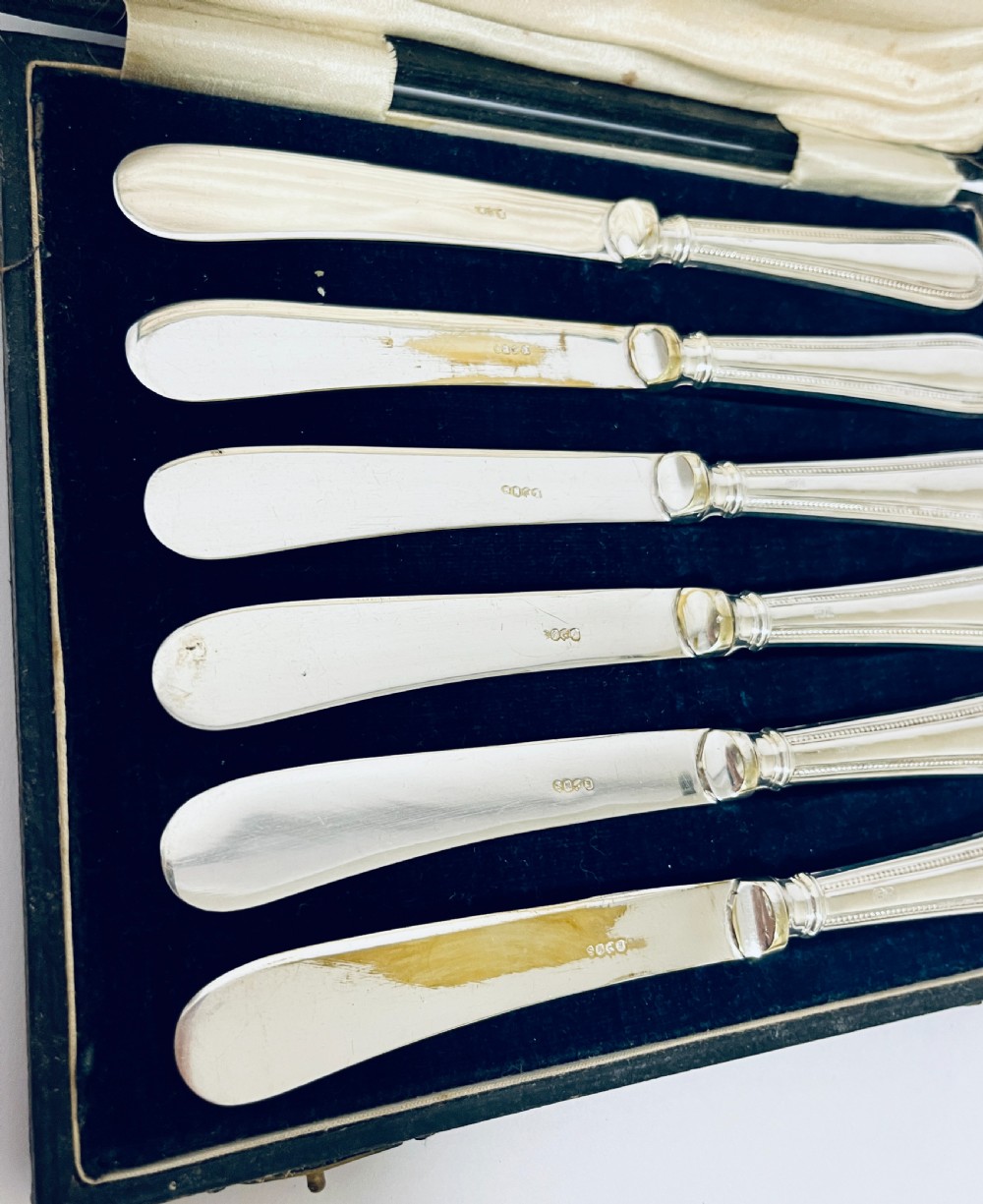 A set of six antique silver-handled butter knives arranged inside a velvet and satin lined presentation case. View IV