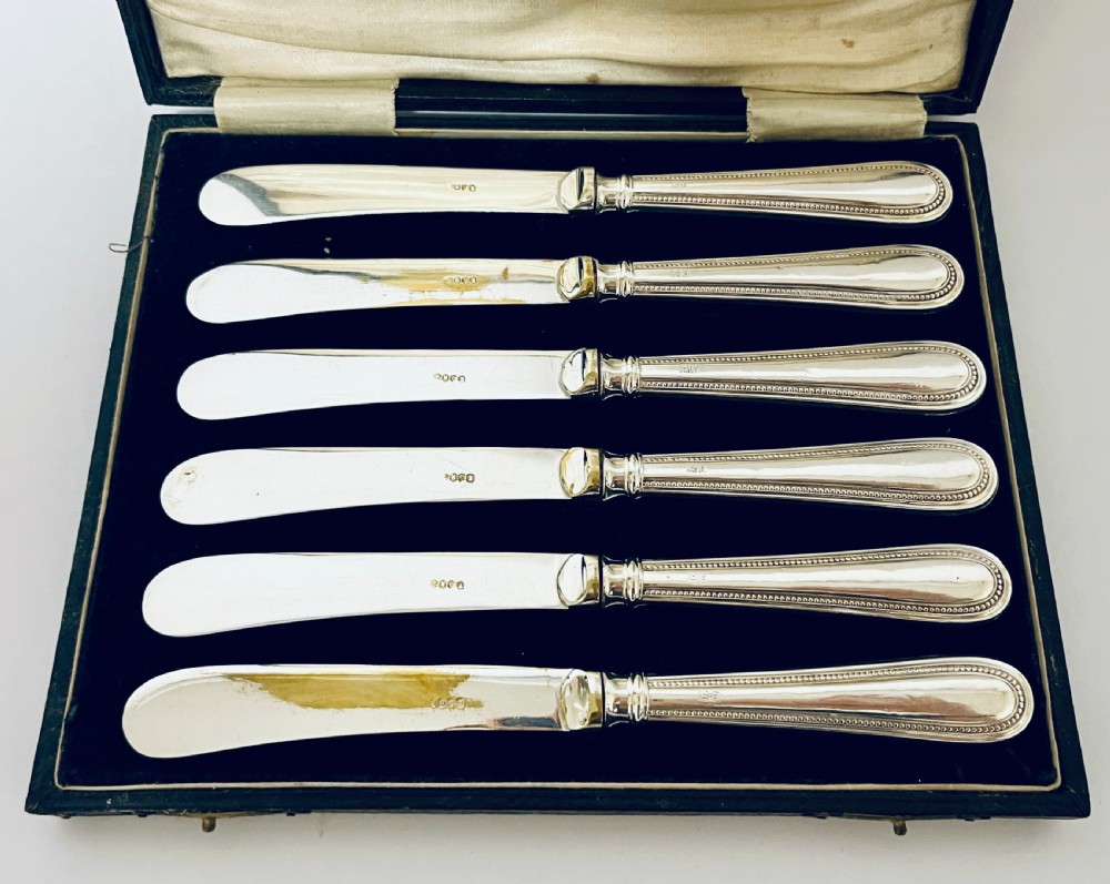 A set of six antique silver-handled butter knives arranged inside a velvet and satin lined presentation case. View V