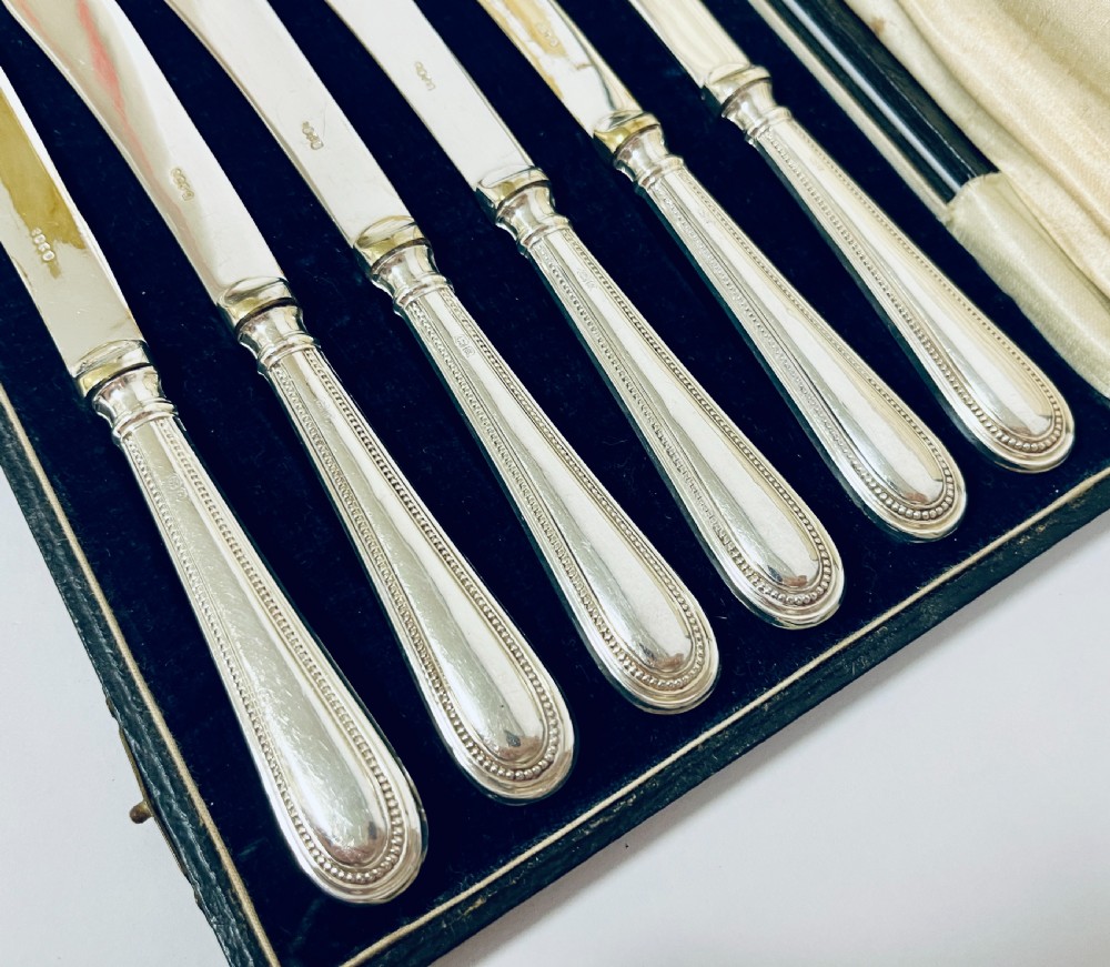 A set of six antique silver-handled butter knives arranged inside a velvet and satin lined presentation case. View VII