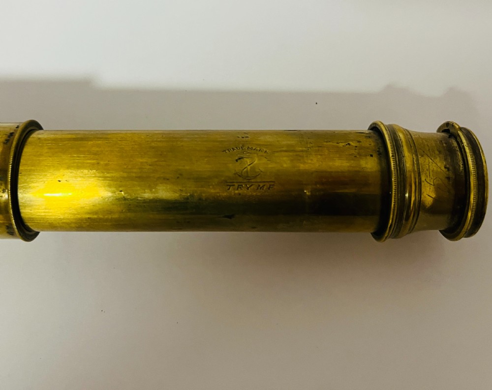 A fully extended three-draw brass telescope featuring a textured black leather sleeve around the main barrel. View II