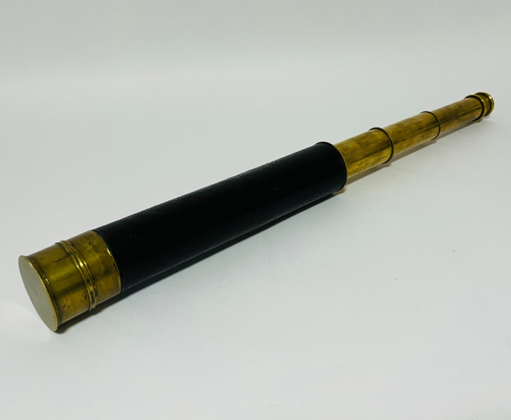 A fully extended three-draw brass telescope featuring a textured black leather sleeve around the main barrel. View III