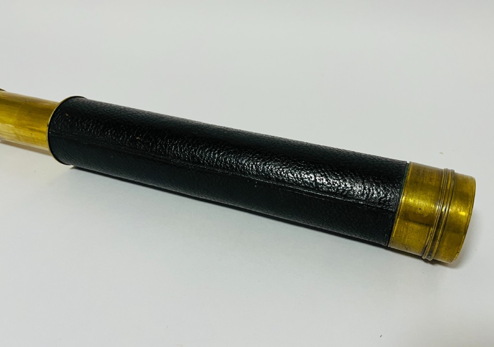 A fully extended three-draw brass telescope featuring a textured black leather sleeve around the main barrel. View VI