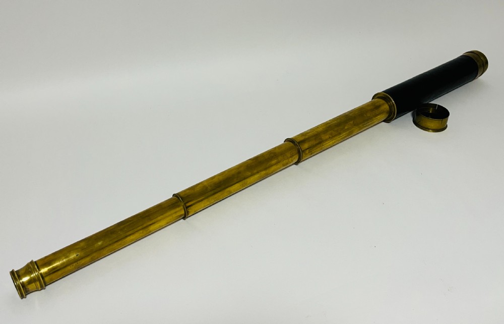 A fully extended three-draw brass telescope featuring a textured black leather sleeve around the main barrel. View VII