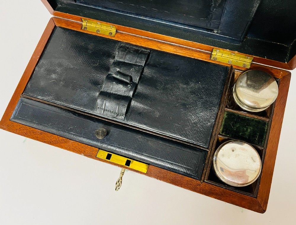 An open Victorian mahogany vanity box featuring a dark leather-lined interior with fitted glass jars topped with silver-coloured lids. View II