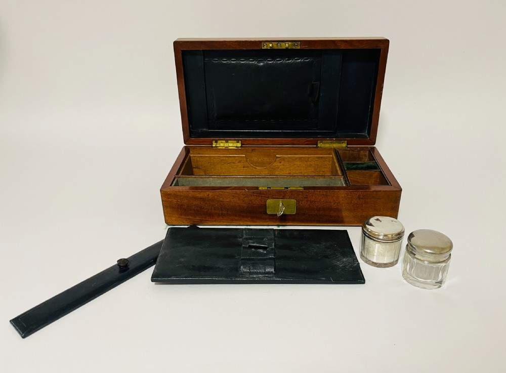 An open Victorian mahogany vanity box featuring a dark leather-lined interior with fitted glass jars topped with silver-coloured lids. View III