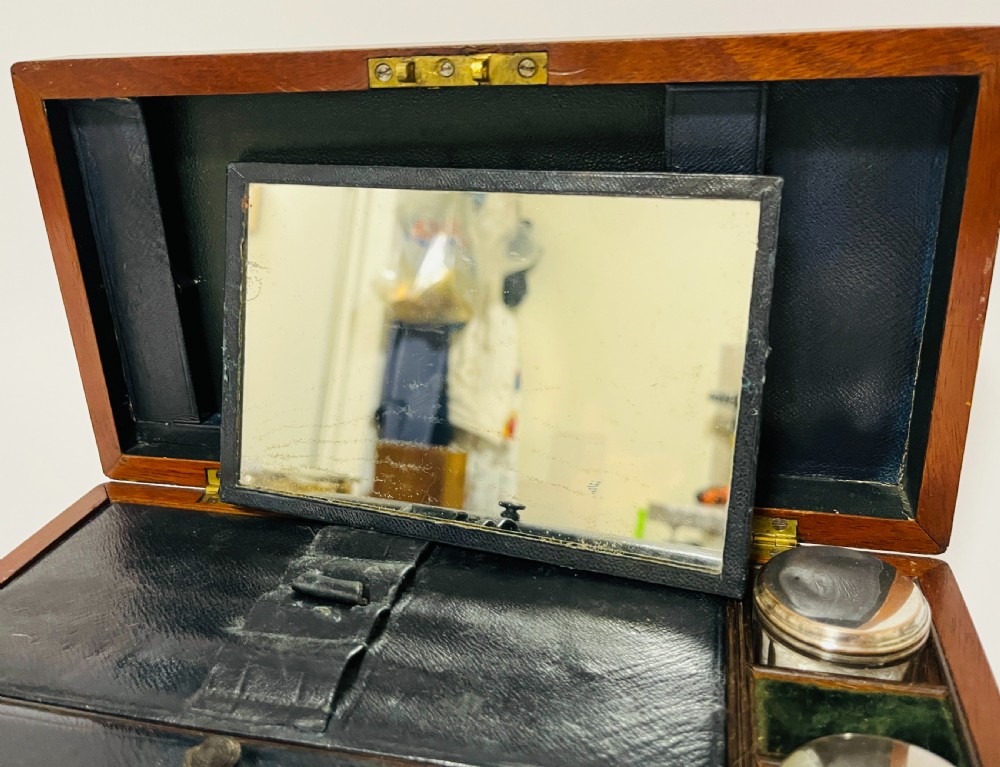 An open Victorian mahogany vanity box featuring a dark leather-lined interior with fitted glass jars topped with silver-coloured lids. View VII