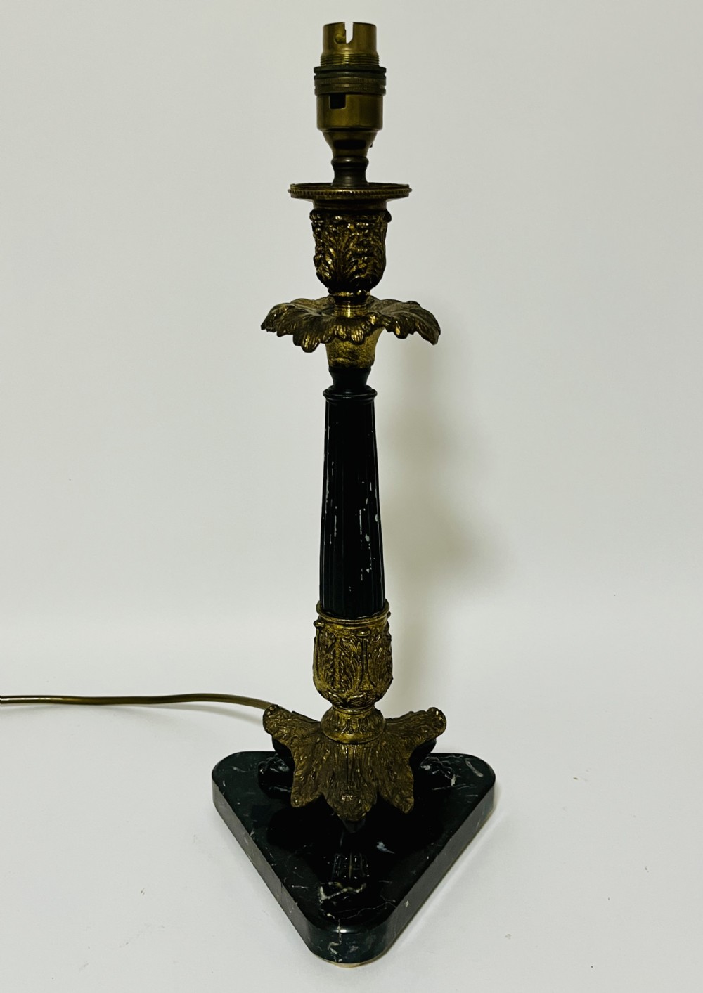 An antique French Empire table lamp featuring a gilt bronze fluted column with acanthus leaf details set upon a triangular black marble base.