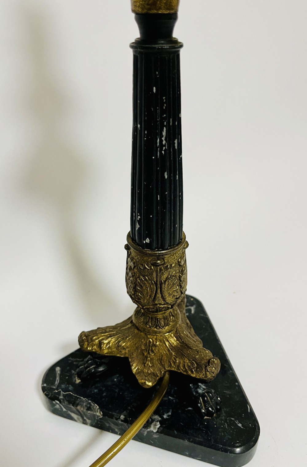 An antique French Empire table lamp featuring a gilt bronze fluted column with acanthus leaf details set upon a triangular black marble base. View IX