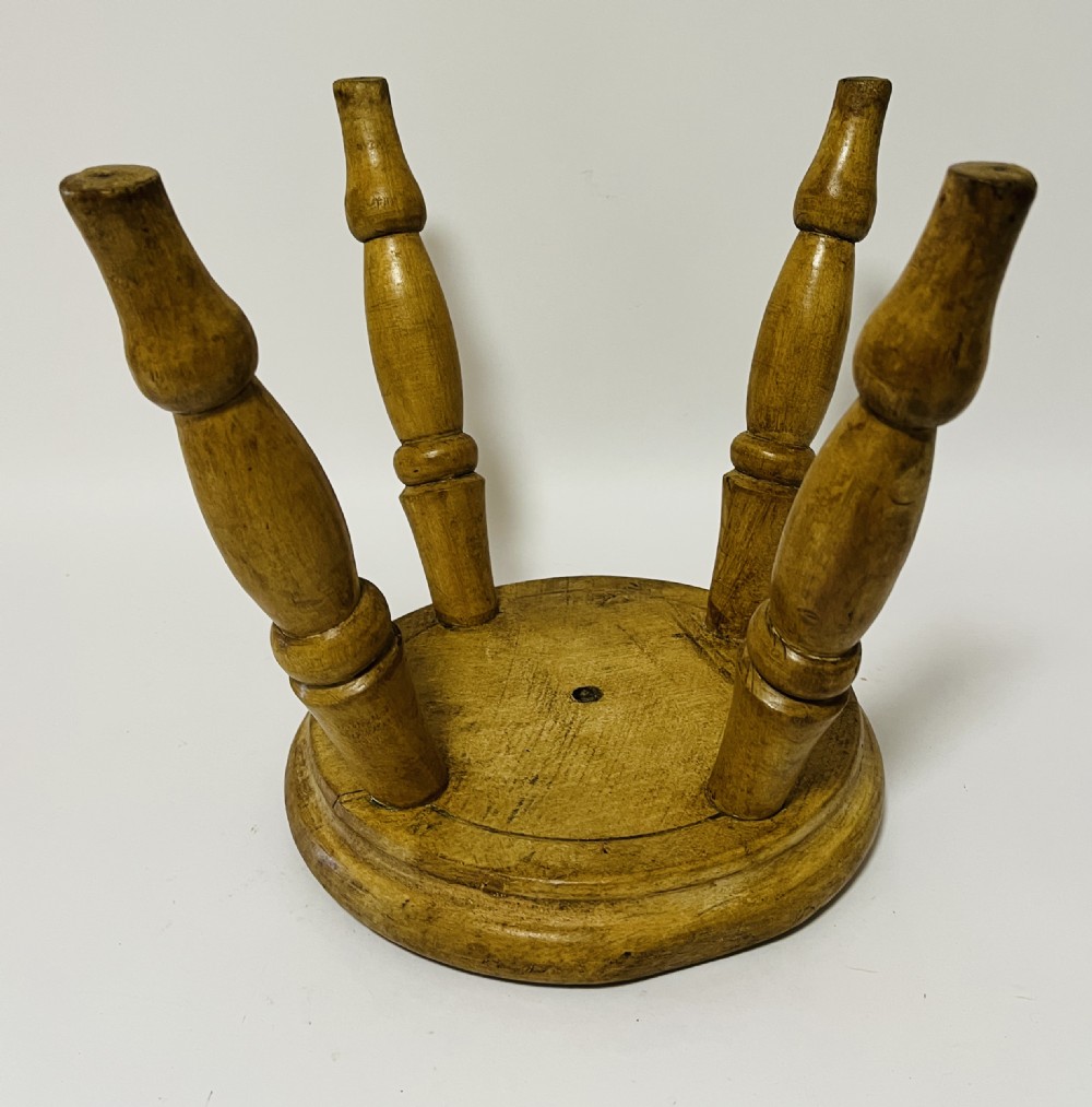 A small antique wooden hearth stool featuring a circular dished seat supported by four splayed turned legs. View VII