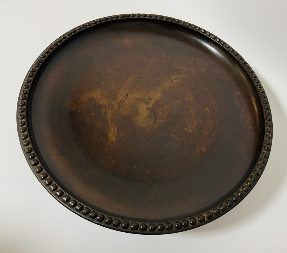 A circular dark wood turned fruit bowl featuring a beaded rim and a raised footed base housing a musical mechanism. View III