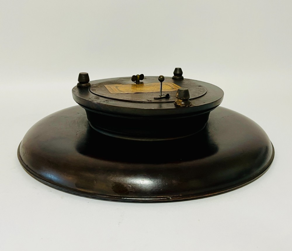 A circular dark wood turned fruit bowl featuring a beaded rim and a raised footed base housing a musical mechanism. View VI