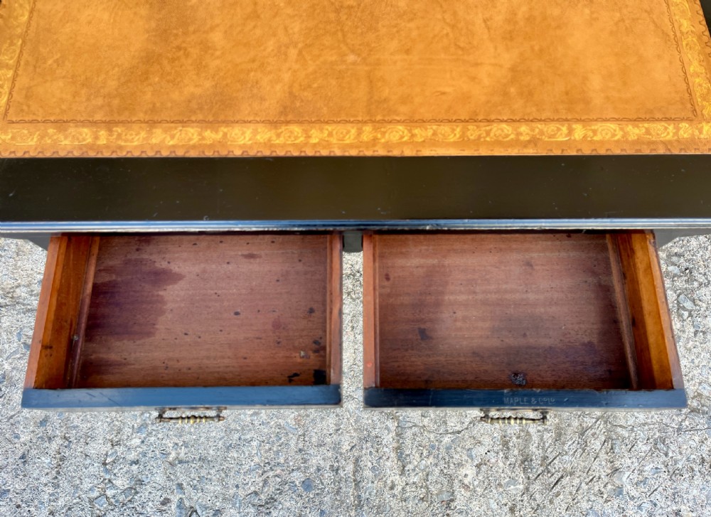 An Aesthetic Movement ebonised writing desk with a tan leather inset top, two frieze drawers with brass handles, and turned spindle legs. View III