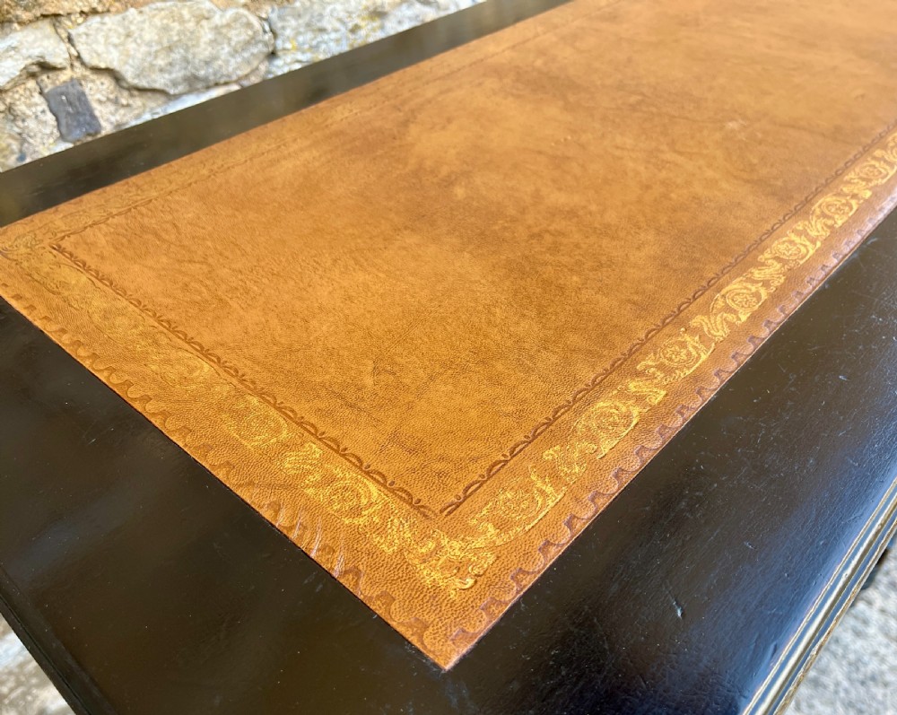 An Aesthetic Movement ebonised writing desk with a tan leather inset top, two frieze drawers with brass handles, and turned spindle legs. View VII