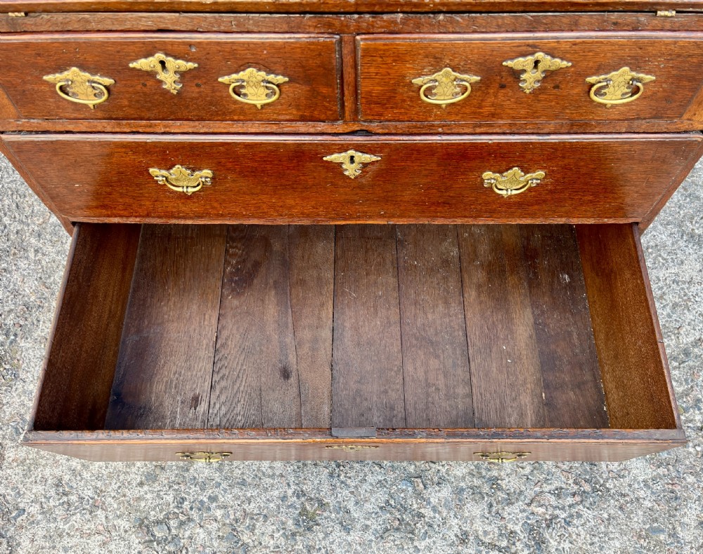 An antique dark oak Georgian bureau featuring a slant front, ornate brass escutcheons, lopers, and bracket feet. View XII