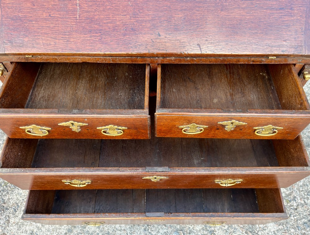 An antique dark oak Georgian bureau featuring a slant front, ornate brass escutcheons, lopers, and bracket feet. View XIII