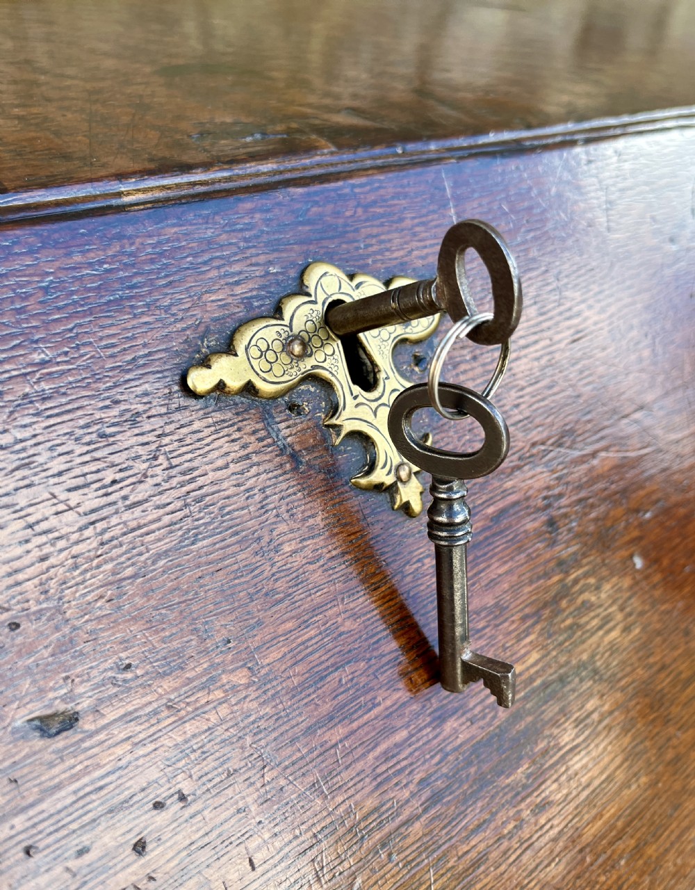 An antique dark oak Georgian bureau featuring a slant front, ornate brass escutcheons, lopers, and bracket feet. View XVIII