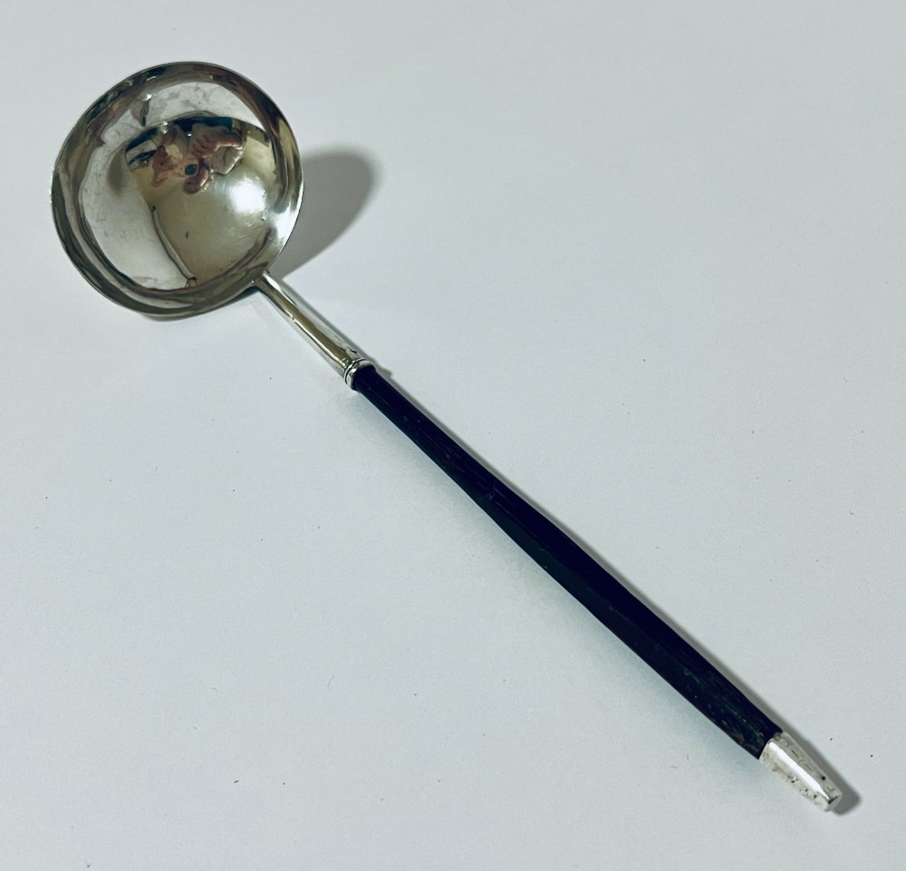 A Georgian Irish silver punch ladle with a circular polished silver bowl and a long turned dark wooden handle. View II