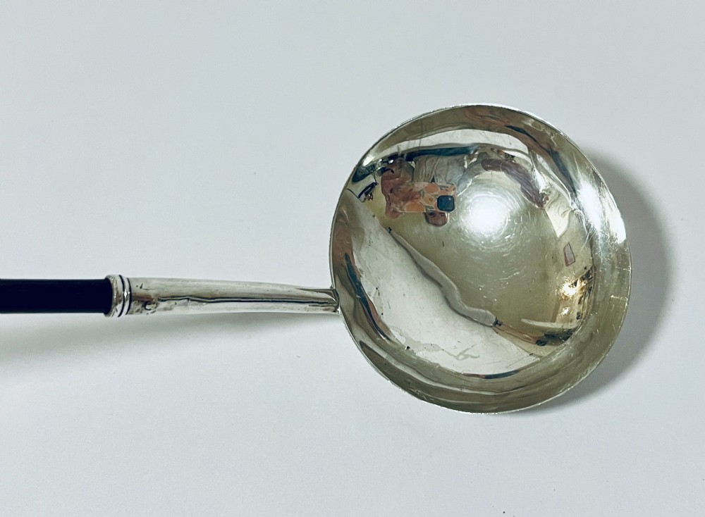 A Georgian Irish silver punch ladle with a circular polished silver bowl and a long turned dark wooden handle. View IV