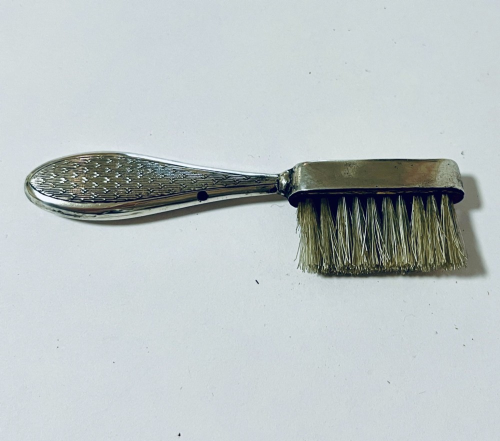 An antique silver moustache brush featuring a textured handle with a central circular cartouche and visible silver hallmarks stamped on the brush head. View V