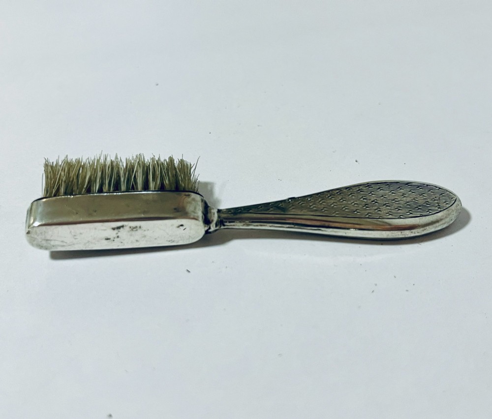 An antique silver moustache brush featuring a textured handle with a central circular cartouche and visible silver hallmarks stamped on the brush head. View VII
