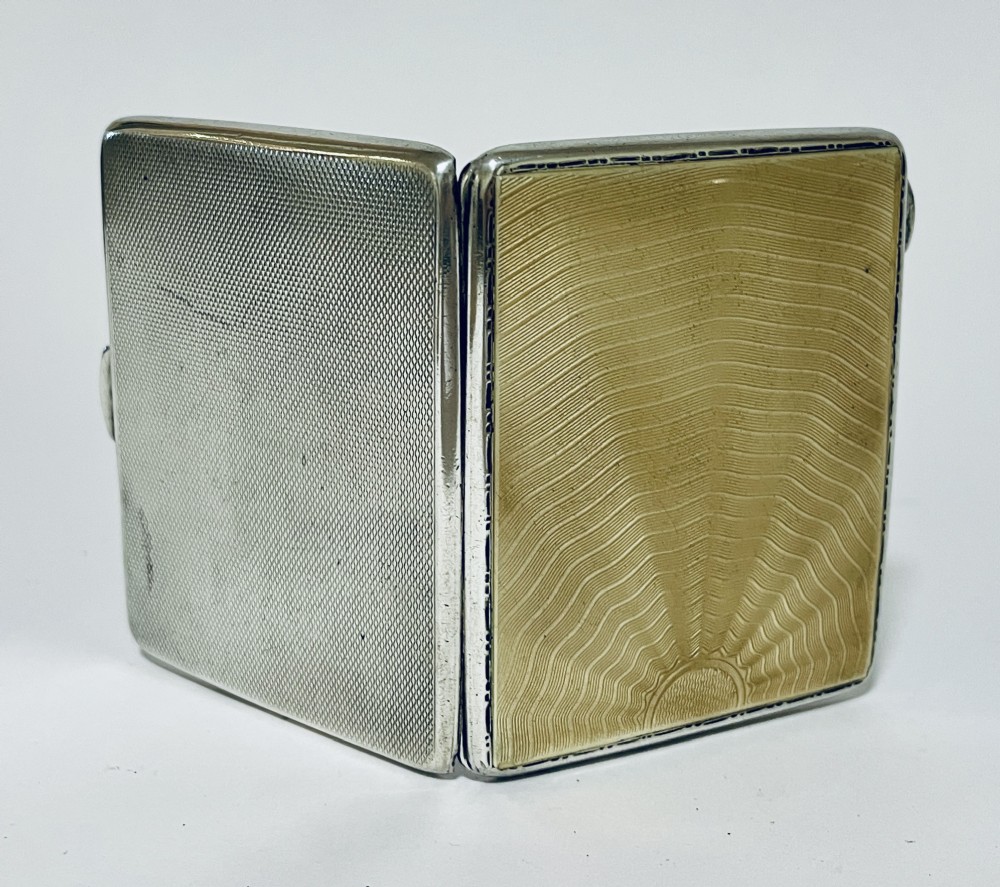 An Art Deco rectangular silver cigarette case featuring a pale yellow translucent enamel panel over a sunburst guilloche pattern. View V