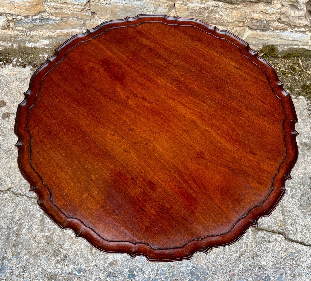 A Georgian mahogany tilt-top side table featuring a scalloped pie-crust edge, turned central column, and carved tripod cabriole legs. View IV