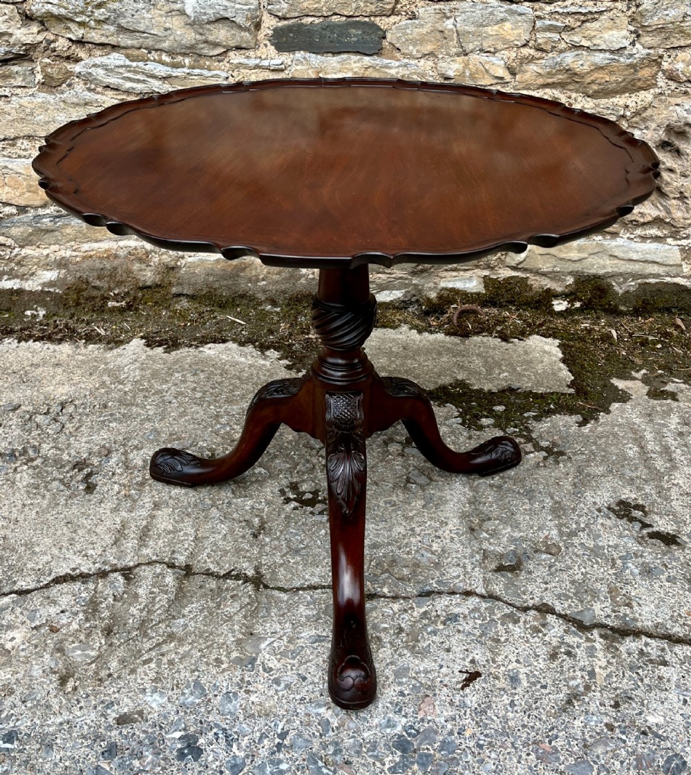 A Georgian mahogany tilt-top side table featuring a scalloped pie-crust edge, turned central column, and carved tripod cabriole legs. View V