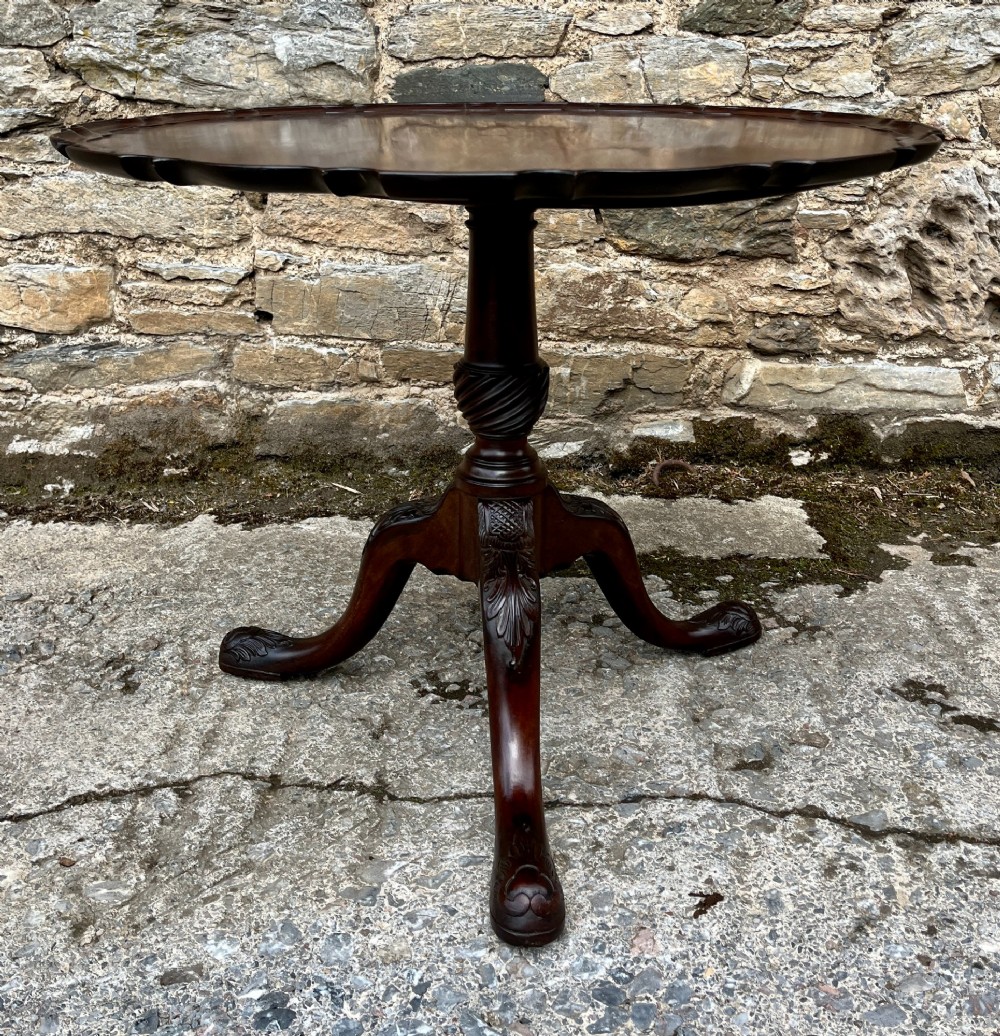 A Georgian mahogany tilt-top side table featuring a scalloped pie-crust edge, turned central column, and carved tripod cabriole legs. View VI