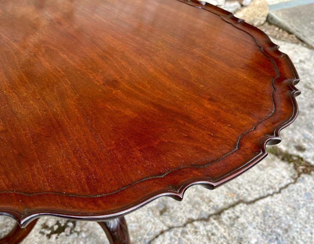 A Georgian mahogany tilt-top side table featuring a scalloped pie-crust edge, turned central column, and carved tripod cabriole legs. View VII
