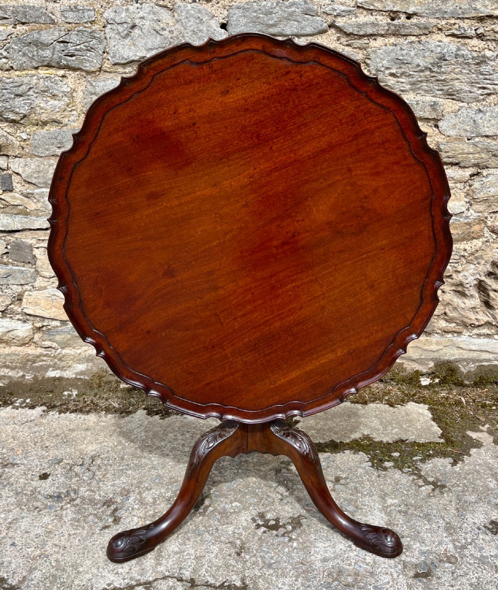 A Georgian mahogany tilt-top side table featuring a scalloped pie-crust edge, turned central column, and carved tripod cabriole legs. View IX