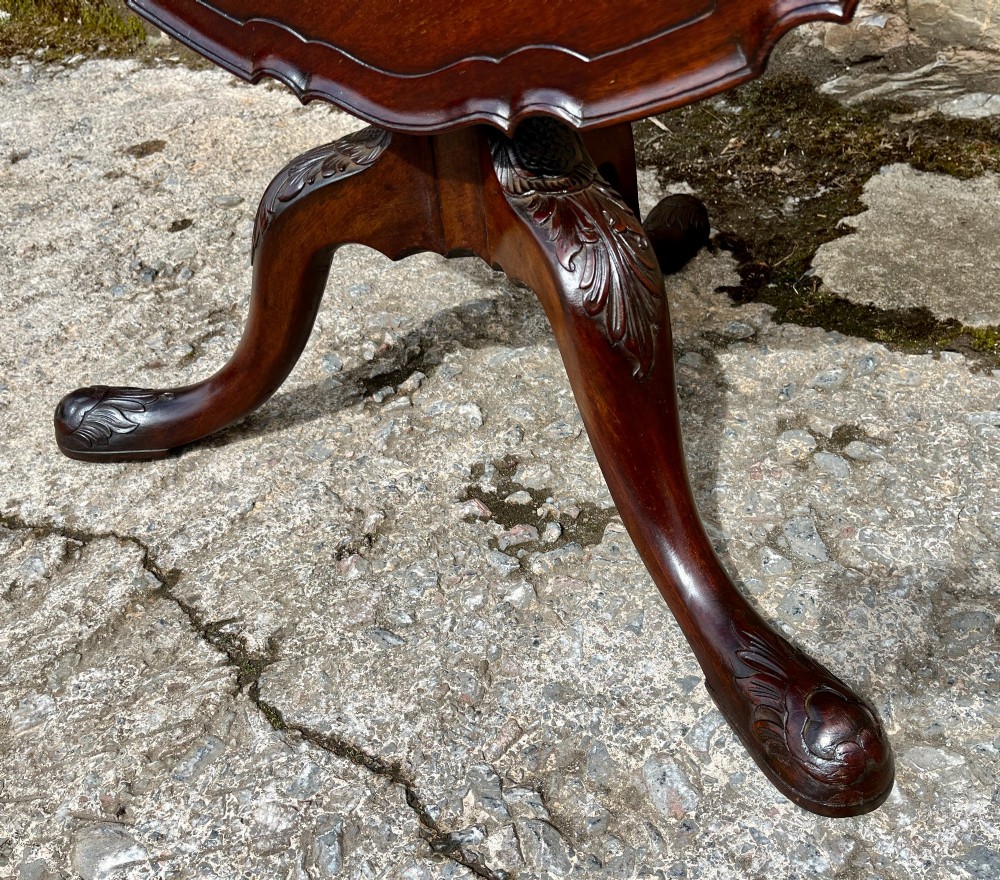A Georgian mahogany tilt-top side table featuring a scalloped pie-crust edge, turned central column, and carved tripod cabriole legs. View X
