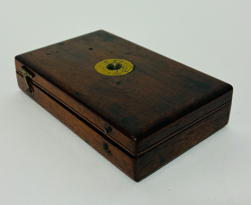 A 19th-century brass botanical field microscope mounted upright on a polished mahogany wooden storage box base. View XI