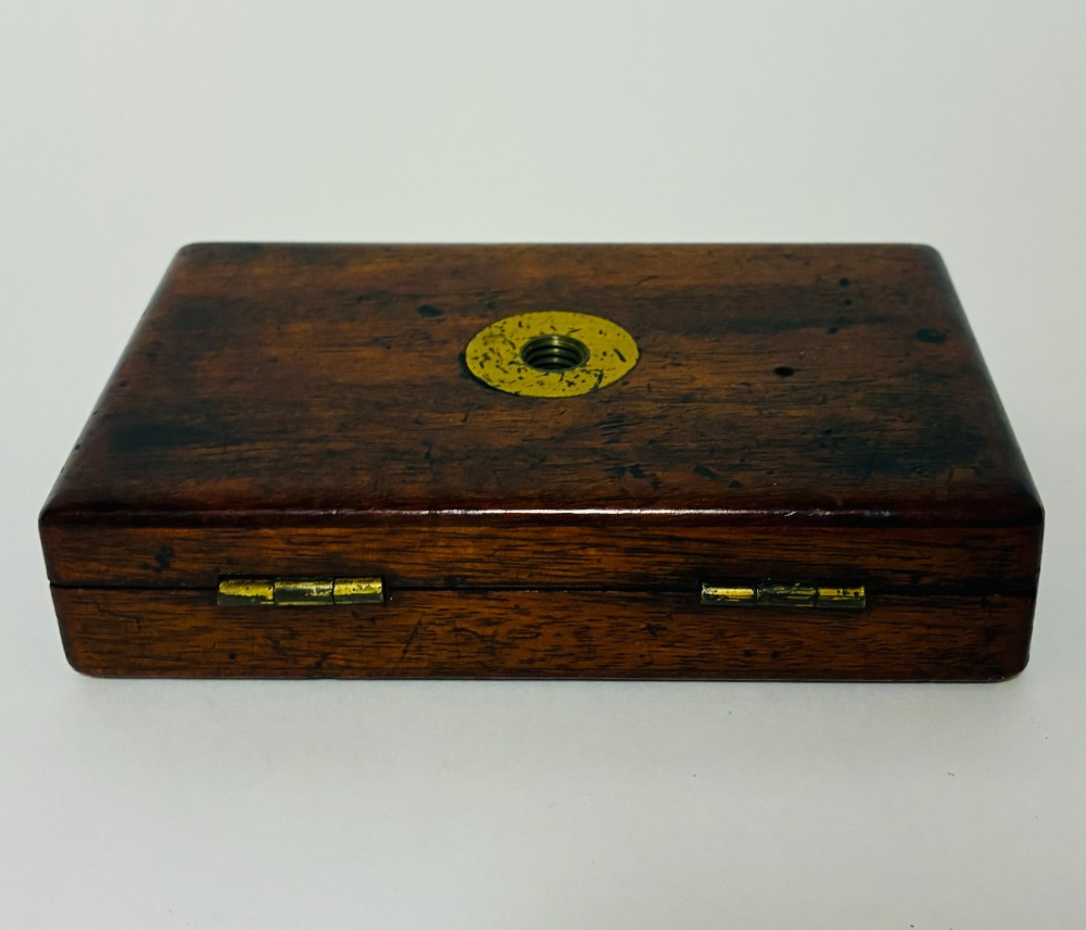 A 19th-century brass botanical field microscope mounted upright on a polished mahogany wooden storage box base. View XII