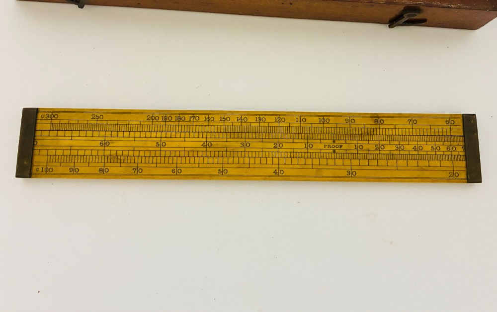A Victorian Sikes hydrometer set resting inside an open fitted mahogany box lined with purple velvet, containing a brass float, slotted weights, and a thermometer. View V