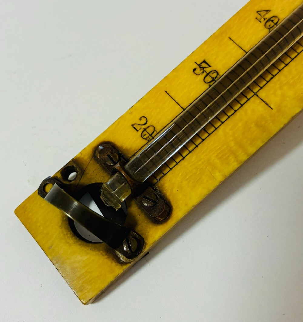 A Victorian Sikes hydrometer set resting inside an open fitted mahogany box lined with purple velvet, containing a brass float, slotted weights, and a thermometer. View VIII