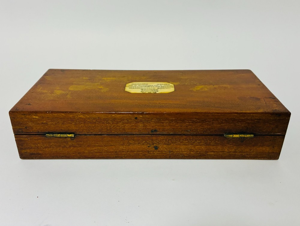 A Victorian Sikes hydrometer set resting inside an open fitted mahogany box lined with purple velvet, containing a brass float, slotted weights, and a thermometer. View XV