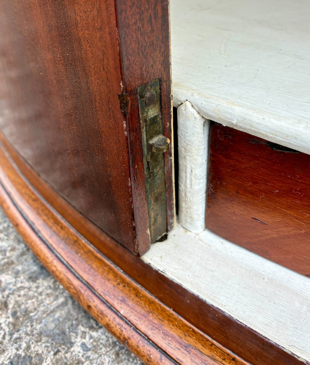 A Georgian bow-front mahogany corner cupboard featuring detailed marquetry inlays, decorative brass hinges, and central keyhole escutcheons. View XI