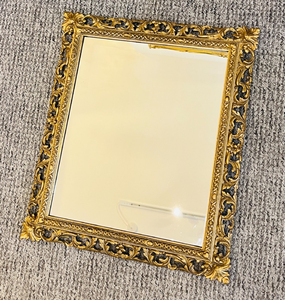 A rectangular wall mirror featuring an ornate pierced giltwood frame decorated with carved acanthus leaf scrollwork and bead moulding. View II