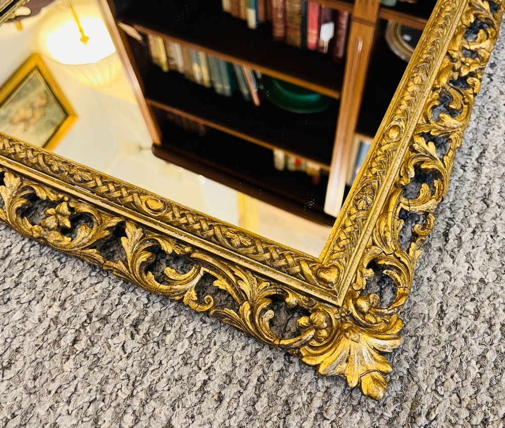A rectangular wall mirror featuring an ornate pierced giltwood frame decorated with carved acanthus leaf scrollwork and bead moulding. View III