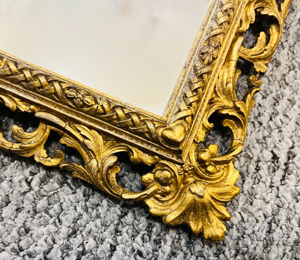 A rectangular wall mirror featuring an ornate pierced giltwood frame decorated with carved acanthus leaf scrollwork and bead moulding. View V