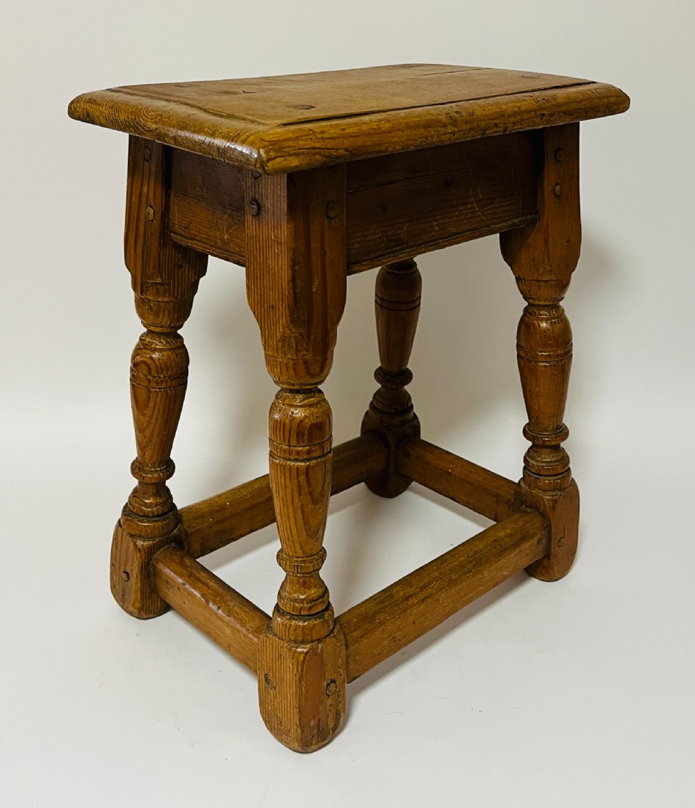 A low rectangular antique pine joint stool with turned legs, base stretchers, and visible wooden dowel construction. View II