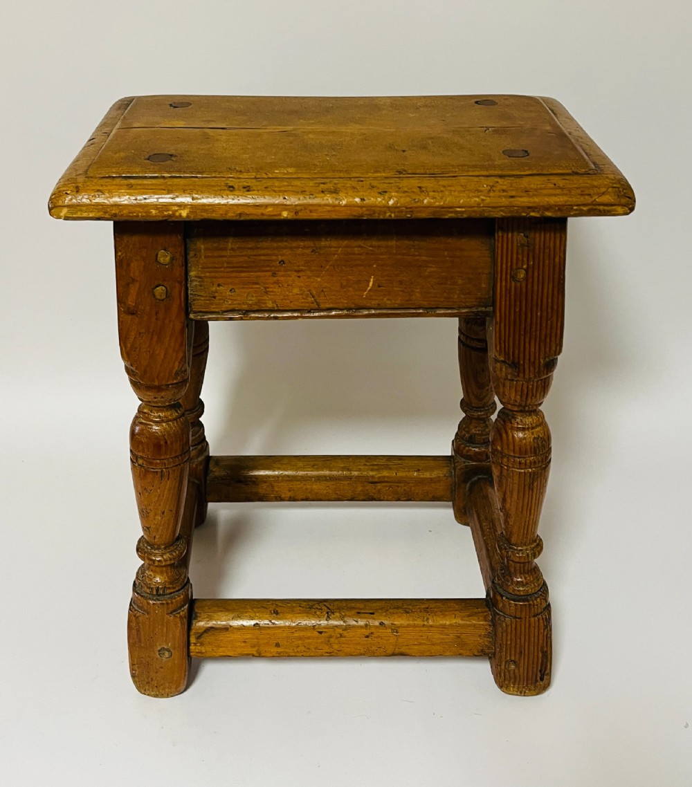 A low rectangular antique pine joint stool with turned legs, base stretchers, and visible wooden dowel construction. View IV