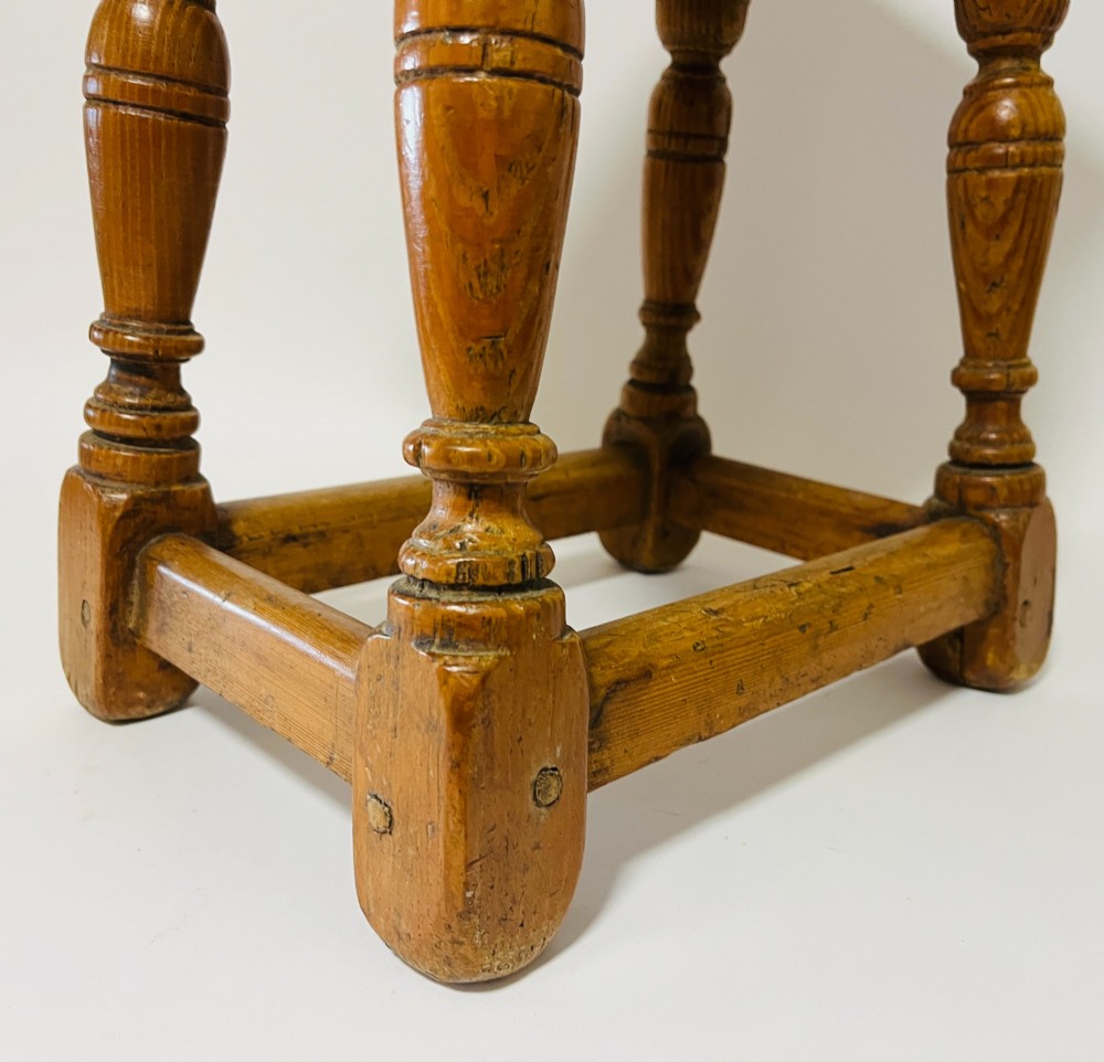 A low rectangular antique pine joint stool with turned legs, base stretchers, and visible wooden dowel construction. View IX