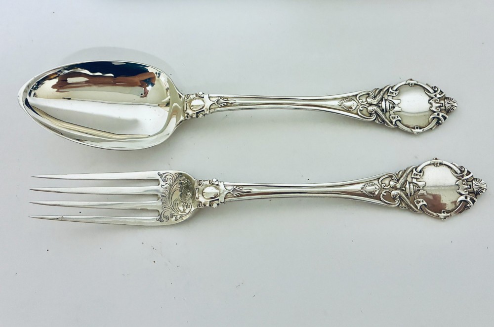 An antique Victorian silver christening spoon and fork with intricate foliate engraving, arranged inside a velvet-lined dark leather presentation case. View III