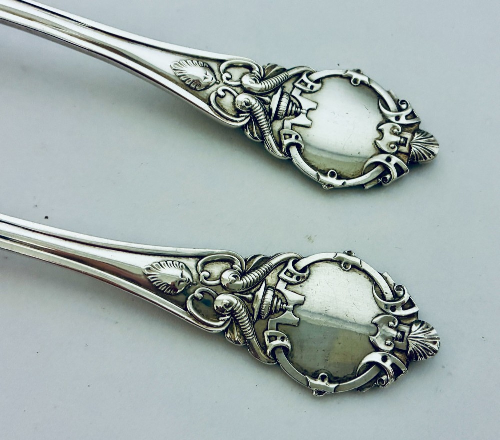 An antique Victorian silver christening spoon and fork with intricate foliate engraving, arranged inside a velvet-lined dark leather presentation case. View IV