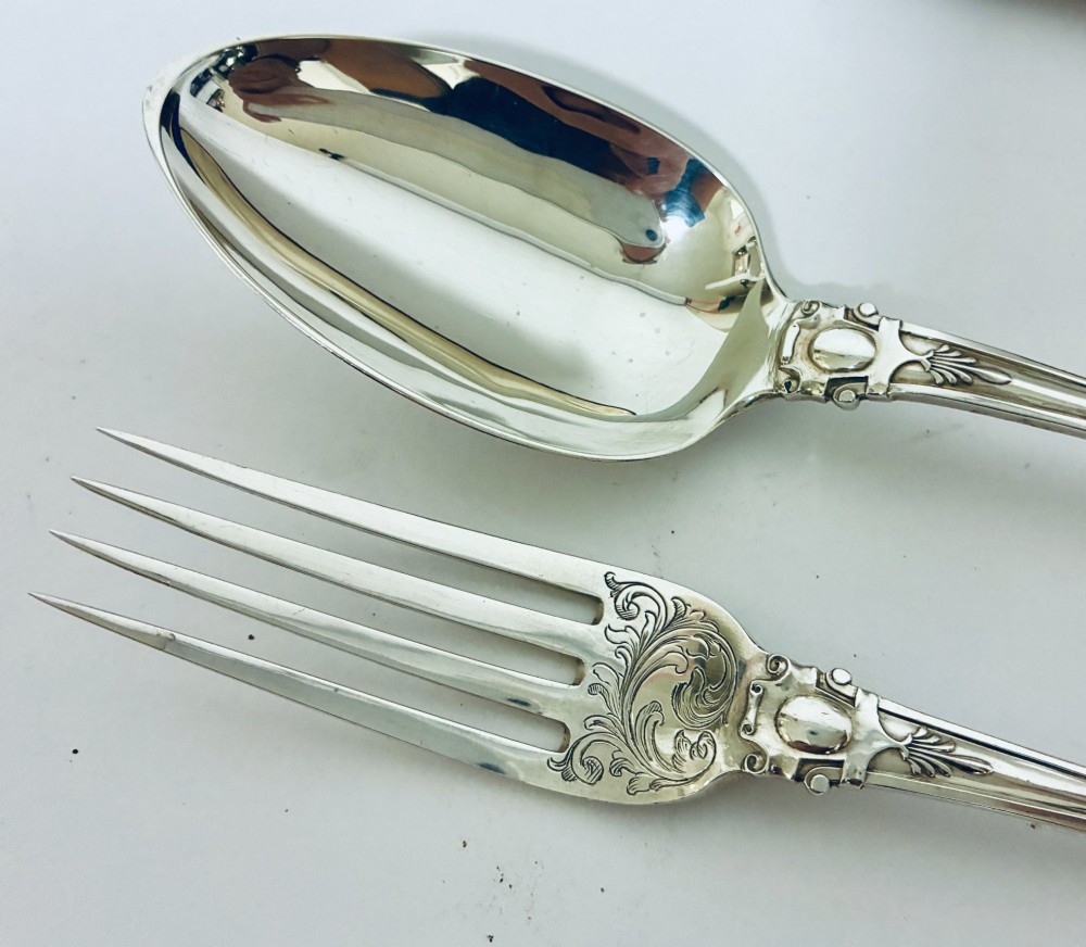 An antique Victorian silver christening spoon and fork with intricate foliate engraving, arranged inside a velvet-lined dark leather presentation case. View V