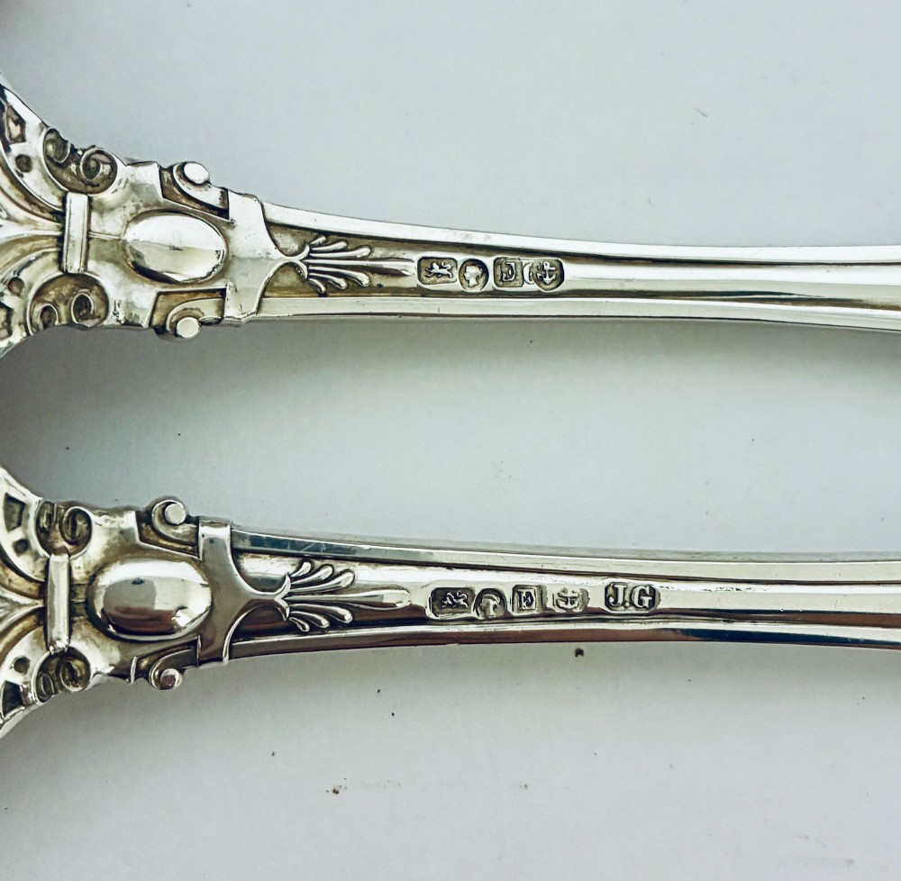 An antique Victorian silver christening spoon and fork with intricate foliate engraving, arranged inside a velvet-lined dark leather presentation case. View IX